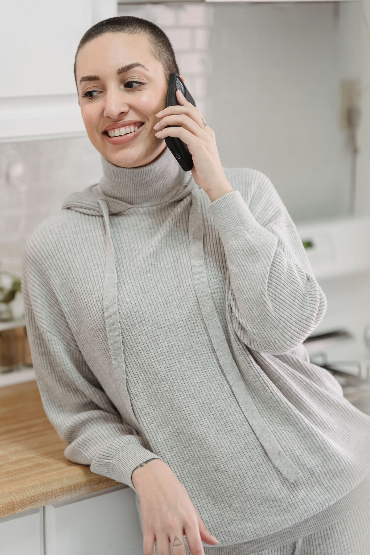 A caregiver relaxes at home with a calm expression during a reassuring phone call